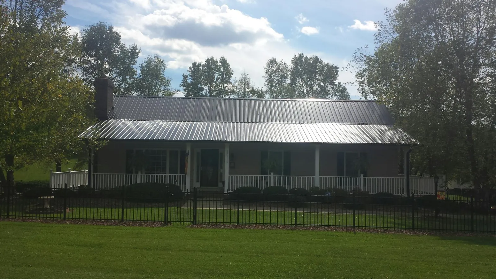 Gray metal roof on a brick ranch with a full width front porch — Gutter Guard Installation work by our crew in Pollock