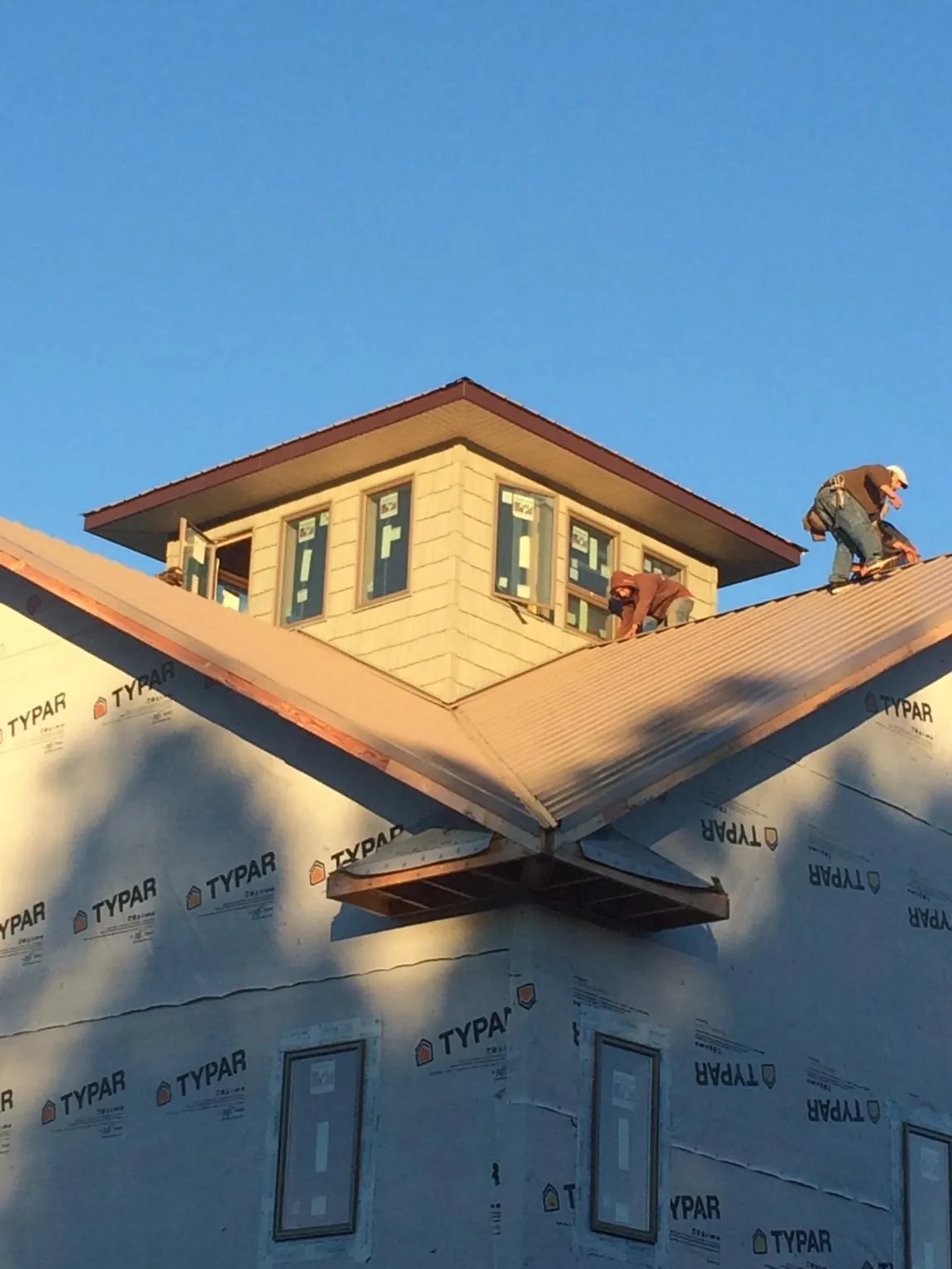 Roofers working around a rooftop cupola on a new metal roof at sunset — Roof Waterproofing in Pollock by Roofing Brothers